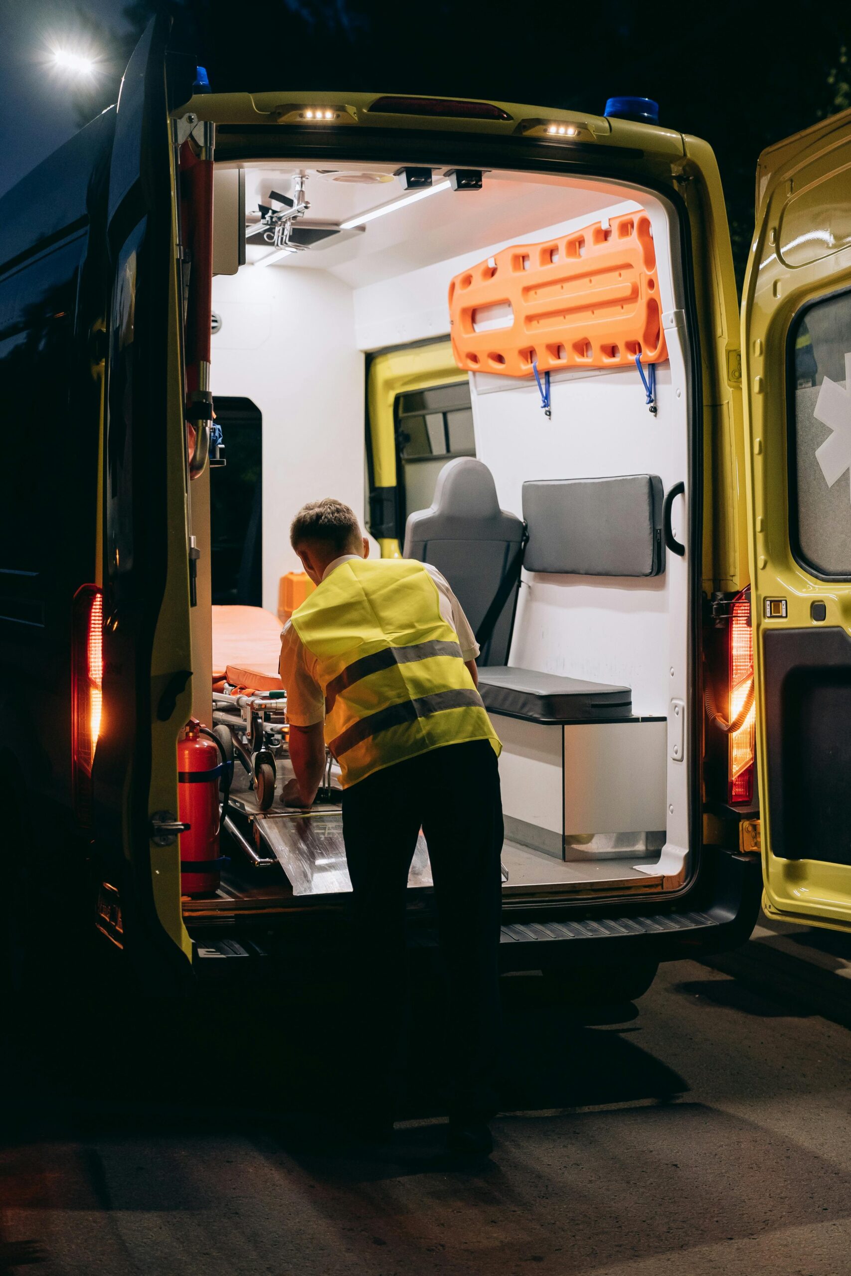 Paramedic preparing to take a gurney out of an ambulance to transport a patient for emergency care