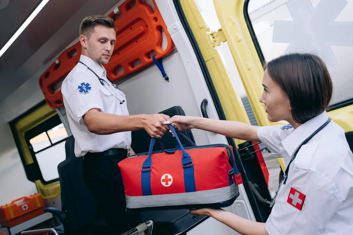 Paramedic handing off a first aid kit from an ambulance to assist with emergency medical care