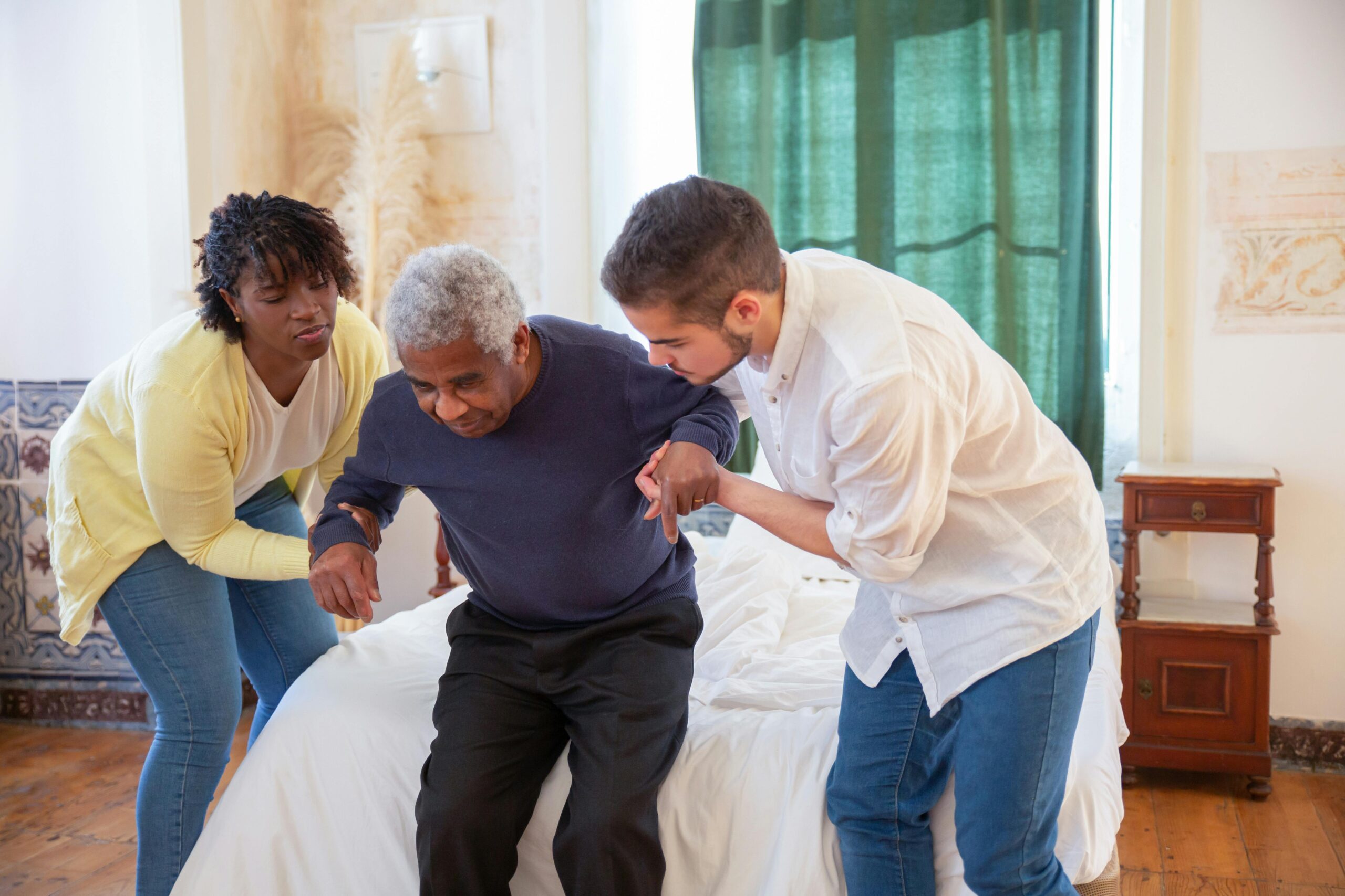 Long-term care center nurses assisting an elderly resident to get up from a bed with gentle support