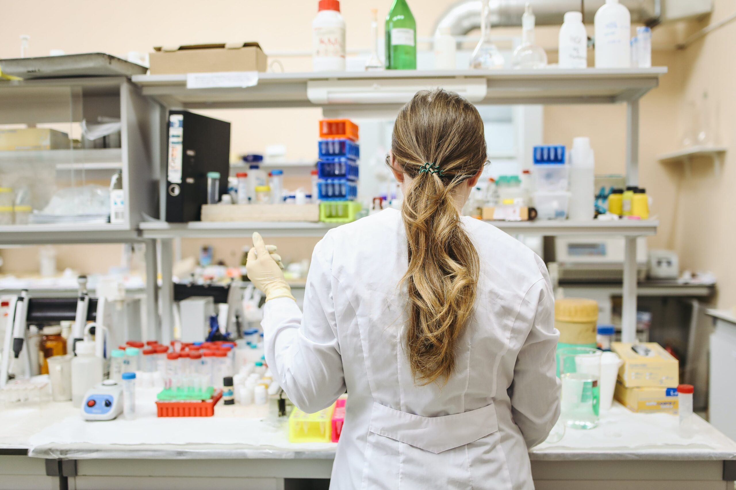 Pharmacist in a white long-sleeved laboratory gown conducting experiments and preparing solutions in a lab